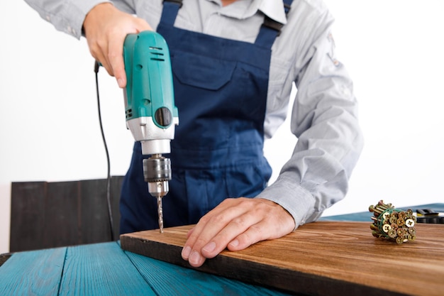 Heimwerker in blauer Uniform arbeitet mit automatischem Schraubendreher der Elektrizität. Konzept der Hausrenovierung.