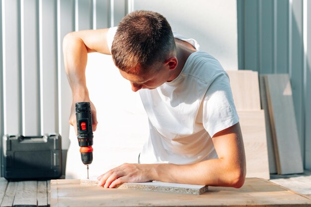 Heimwerker in blauer Uniform arbeitet mit automatischem Schraubendreher des Stroms