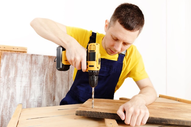 Heimwerker in blauer Uniform arbeitet mit automatischem Schraubendreher des Stroms