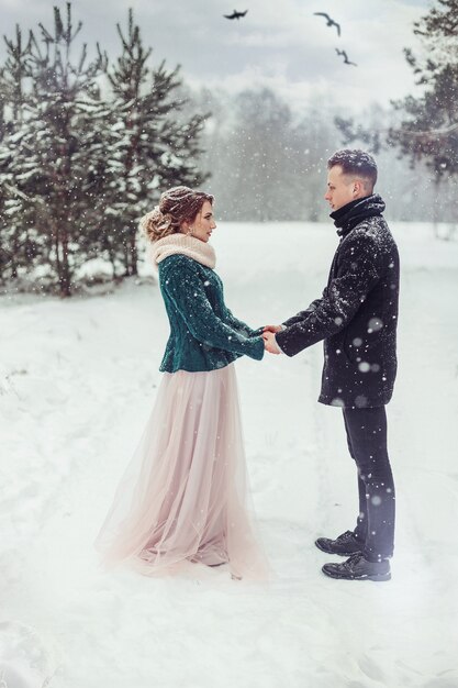 Heiratende liebevolle Paare im schneebedeckten Wald des Winters