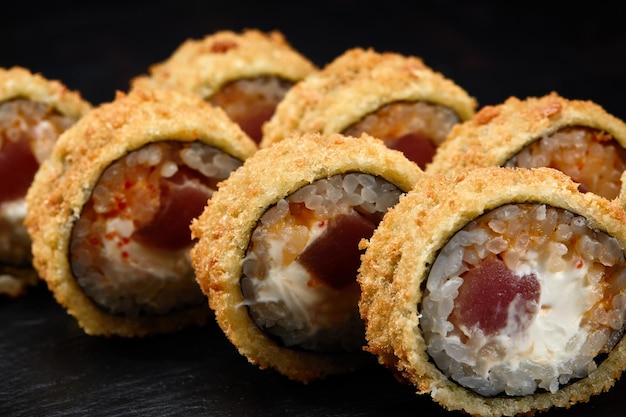 Heiß gebratene Sushi-Rolle mit Lachs Sushi-Menü Japanisches Essen Heiß gebratene Sushi-Rolle auf schwarzem Hintergrund