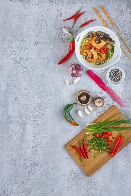 Heiße asiatische Wok-Nudeln mit Garnelen und Pilzen, Zubereitung Ramen, grauer Hintergrund, Kopierraum