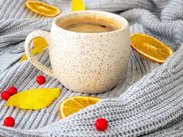 Heiße dampfende Tasse Kaffee und ein gemütlicher Pullover