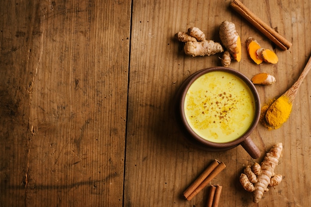 Heiße Gelbwurzmilch mit Gewürzen auf Holztisch