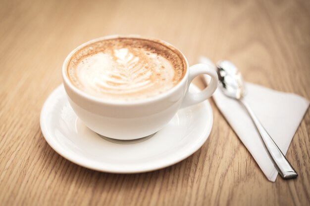 Heiße Kaffeecappuccino Lattekunst auf hölzernem Hintergrund