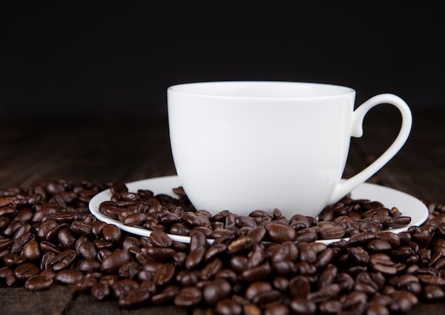 Heiße Kaffeetasse auf Bohnen zum Frühstücksmorgen auf hölzernem Brett