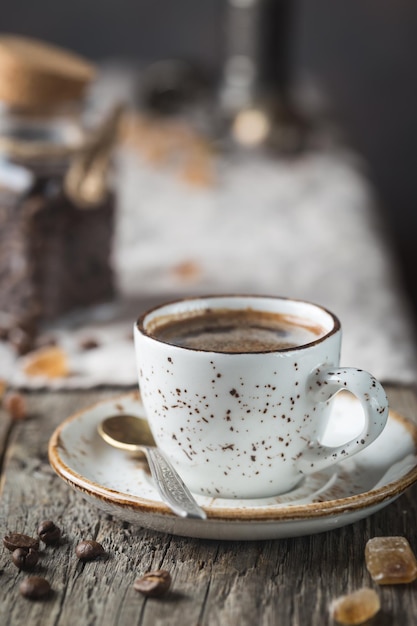 Heiße Kaffeetasse und Kaffeebohnen auf dem Holztisch, rustikaler Stil