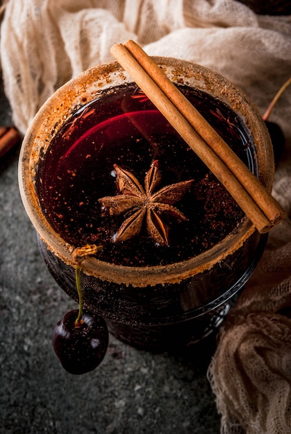 Heiße Kirschsangria mit Zimt, Anis, Wein und Gewürzen auf einem Stein