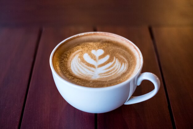 Heiße Latte-Kaffeetasse-Herzform auf Holztisch