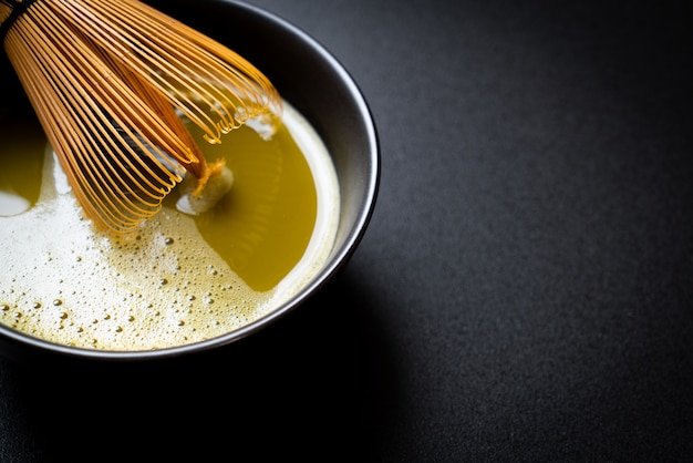 Foto heiße matcha-grüntee-tasse mit grüntee-pulver und schneebesen