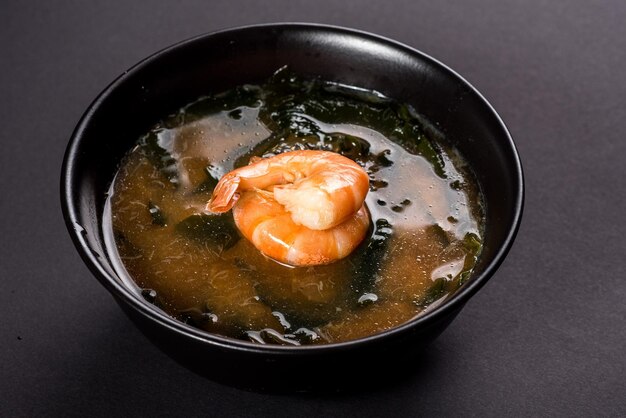 Heiße Miso-Suppe mit Garnelen in Schüssel auf schwarzem Hintergrund Japanisches Essen