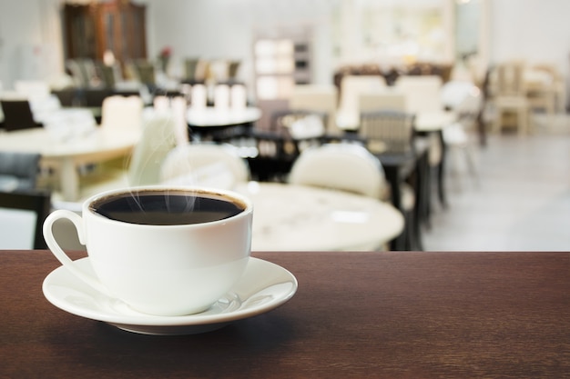 Heiße schale schwarzer kaffee auf tischplatte im café. drinnen.