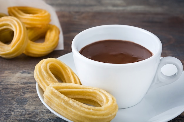 Heiße Schokolade mit Churros auf spanischem Frühstück des Holztischs