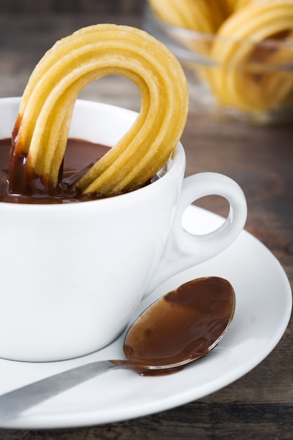 Heiße Schokolade mit Churros auf spanischem Frühstück des Holztischs