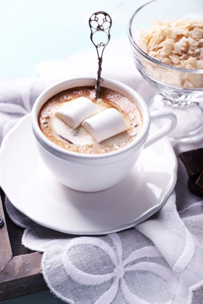 Heiße Schokolade mit Marshmallows im Becher, auf farbigem Holzhintergrund