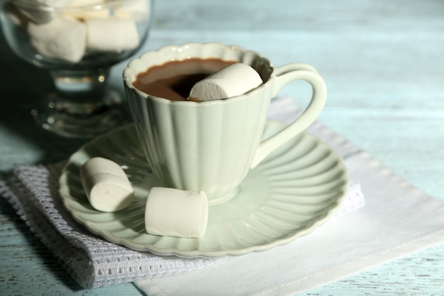 Heiße Schokolade mit Marshmallows im Becher, auf farbigem Holztisch, auf hellem Hintergrund