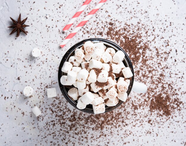 Foto heiße schokolade mit marshmallows und einer roten papierröhre auf einem grauen tisch. weihnachtsfoto. draufsicht und makro