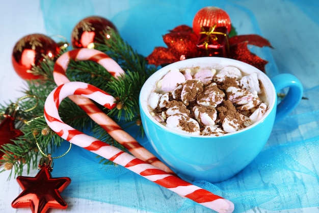 Heiße Schokolade mit Sahne im Farbbecher, auf dem Tisch, auf der Weihnachtsdekoration