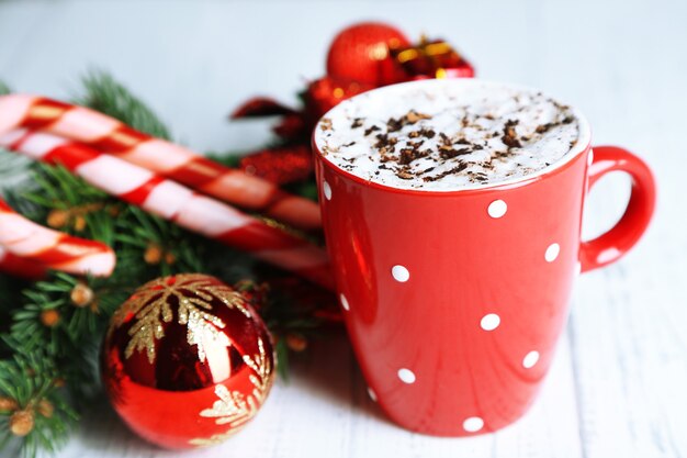 Heiße Schokolade mit Sahne im Farbbecher, auf dem Tisch, auf Weihnachtsdekorationshintergrund