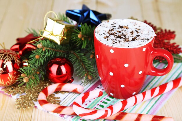 Heiße Schokolade mit Sahne im Farbbecher, auf dem Tisch, auf Weihnachtsdekorationshintergrund