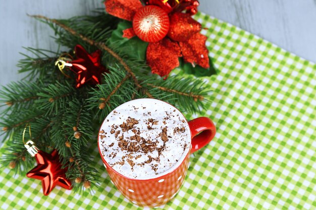 Heiße Schokolade mit Sahne im Farbbecher, auf Serviette, auf Weihnachtsdekorationshintergrund