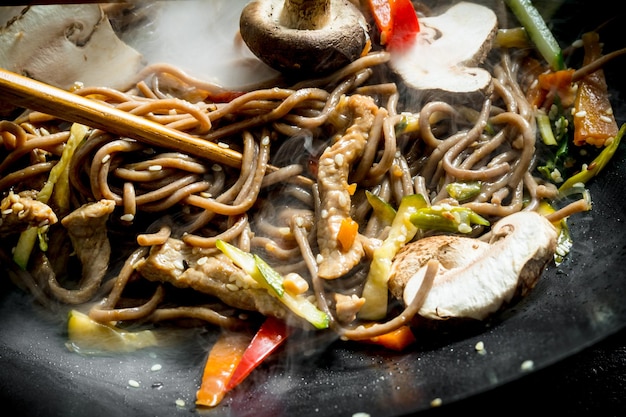 Foto heiße sobanudeln in einer wokpfanne mit pilzsauce und rindfleisch