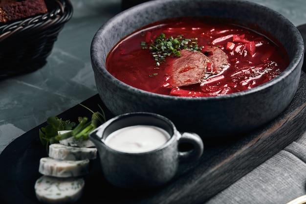 Heiße Suppe. Borschtsch mit roten Bohnen und geschmortem Rindfleisch. Bequemes Essen. Serviert mit Schwarzbrot und Schweinefett im rustikalen Stil.