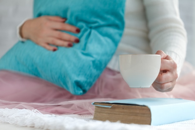 Heiße Tasse Tee mit Frauenhänden im Retro-Wollpullover