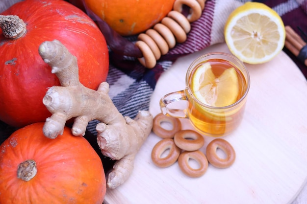 Heiße Tasse Tee mit Herbstlaub, Kürbissen, Ingwer, Zitrone und Bagels. Herbststimmung. Erwärmendes Getränk