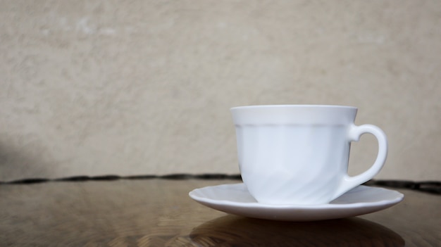 Heißer aromatischer Kaffee mit Milch. Frisch zubereitetes Getränk wird in einer modernen Tasse auf einem hellen Korbtisch serviert.