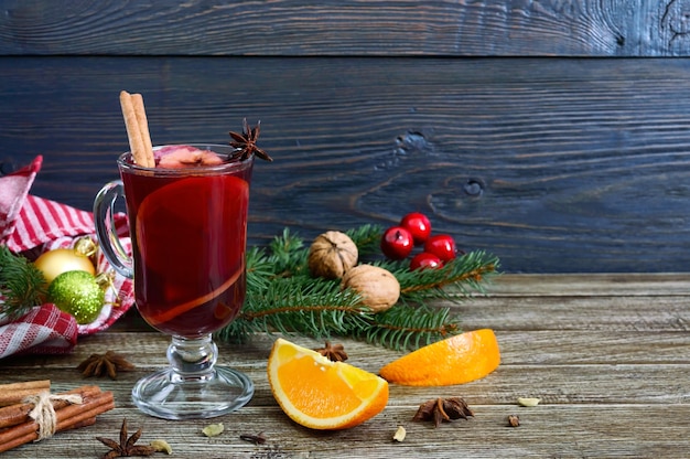 Heißer Glühwein im Glasbecher auf einem Holztisch. Duftendes traditionelles Wintergetränk basierend auf Wein, Saft, Gewürzen, Gewürzen, Früchten.