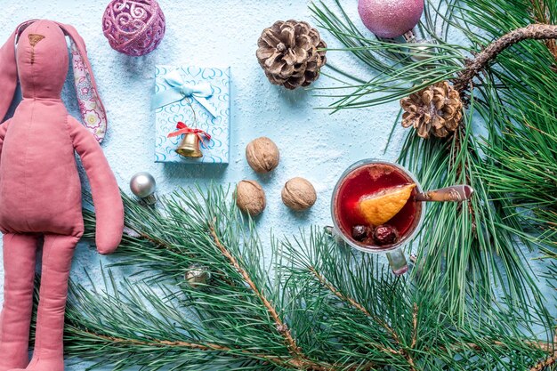 Heißer Glühwein mit Orangenanis Kardamom und Zimt auf blauem Hintergrund Weihnachtsbaum Zweige Geschenke und Zapfen