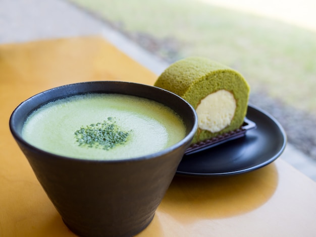 Heißer grüner Tee Matcha Latte und Rollenkuchen des grünen Tees auf Holztisch