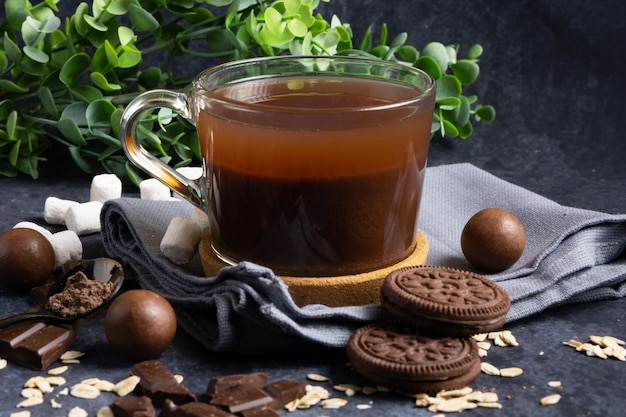 Heißer Haferflocken-Kakao in einem klaren Glasbecher mit Keksen und Pralinen Gesundes Getränk