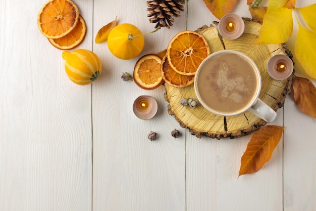 Heißer Herbstgetränkkaffee oder -kakao mit gelben Blättern und dekorativen Kürbisen auf einer Draufsicht der weißen Holztischherbstzusammensetzung