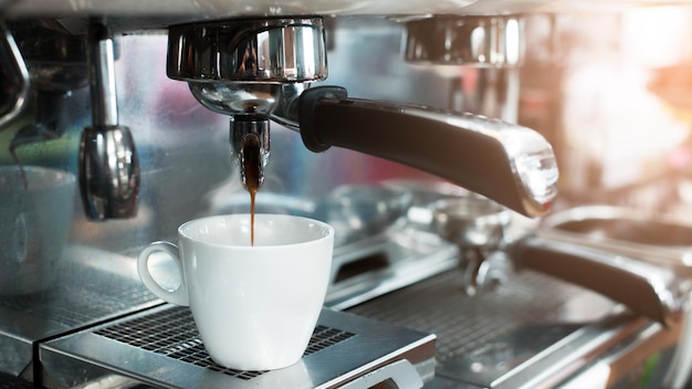 Heißer Kaffee auf einem Tisch mit Sahne, die hineingegossen wird und die Textur zeigt