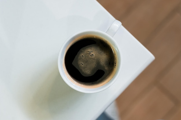 Heißer Kaffee auf einem Tisch mit Sahne, die hineingegossen wird und die Textur zeigt