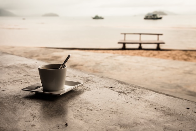 Heißer Kaffee auf tropischem Strandhintergrund