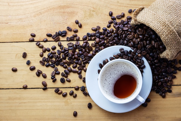 Heißer Kaffee Espresso oder Americano und Kaffeebohne auf älterem Holztisch zur Morgenzeit. Kaffeepause Zeit.