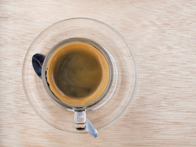 Heißer Kaffee im Klarglas auf Bretterboden morgens. Draufsicht