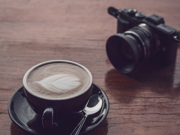 Heißer Kaffee in der schwarzen Schale mit Kamera