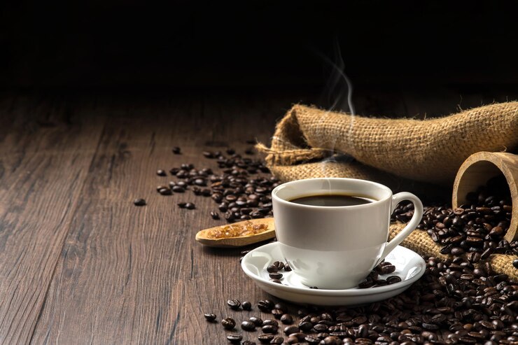 Heißer Kaffee in einer weißen Kaffeetasse und viele Kaffeebohnen, die herumgelegt sind, und Zucker auf einem Holzbecher