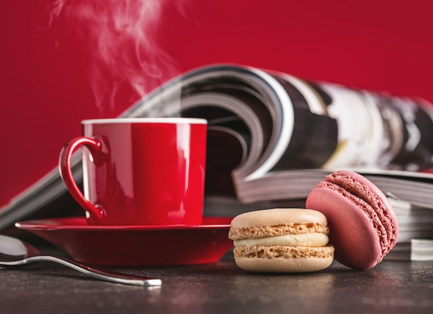 Heißer Kaffee in roter Tasse, Kekse und Zeitschriften.