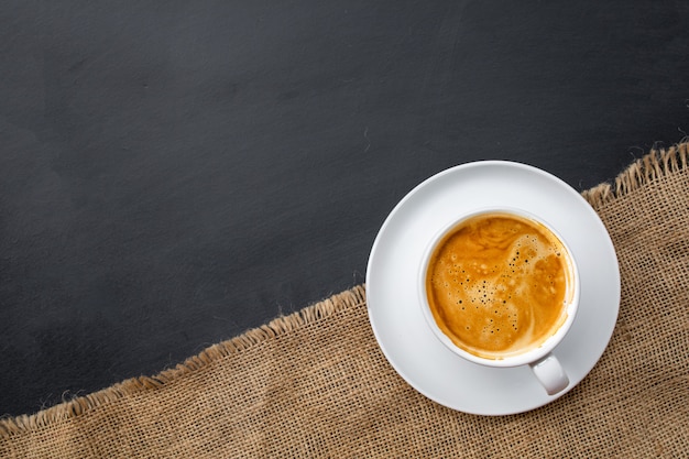 Heißer Kaffee in weißer Tasse auf Sackleinen