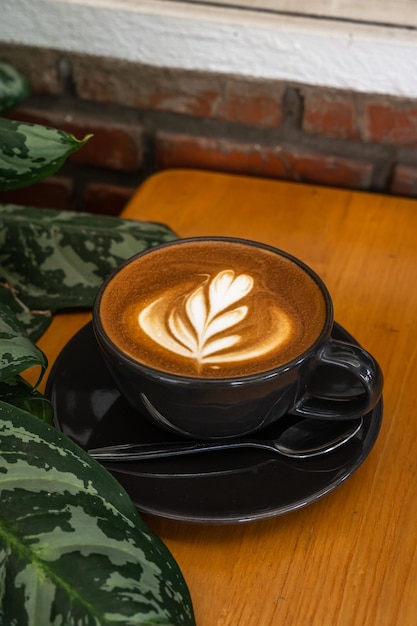 Heißer Kaffee Latte mit Latte Art Milchschaum in Tasse Becher auf Holzschreibtisch in der Draufsicht Als Frühstück in einem Café im Cafeduring Business Work Concept