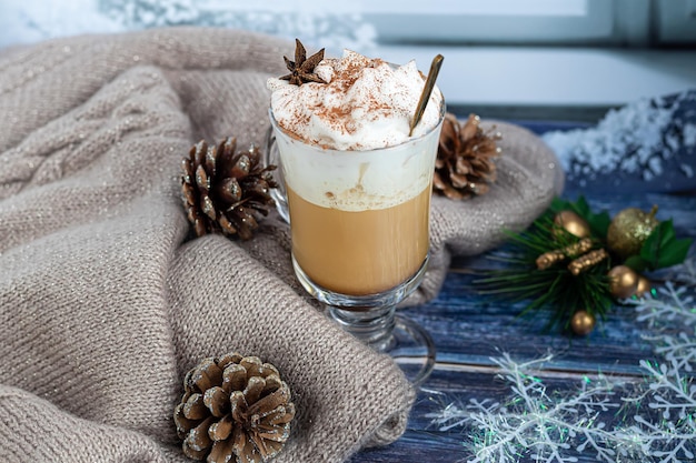 Heißer Kaffee Latte mit Zimtstangen, mit Zimt bestreut. Weihnachtsschmuck, Zweige eines Weihnachtsbaums. Feiertagskonzept Neues Jahr. Auf einem hölzernen Hintergrund.