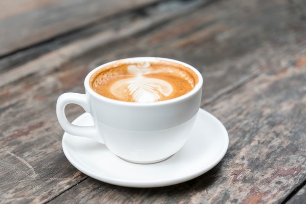 Heißer Kaffee mit später Kunst auf Holztisch