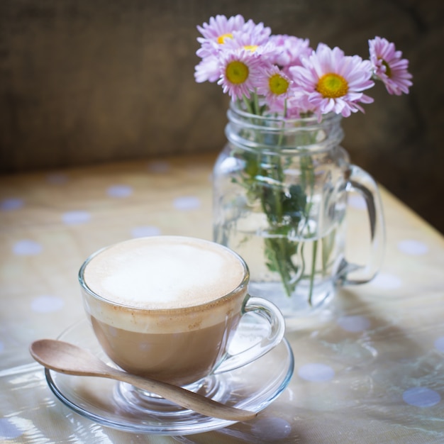 Heißer Kaffee und Blumenstrauß auf grunge Holztisch.