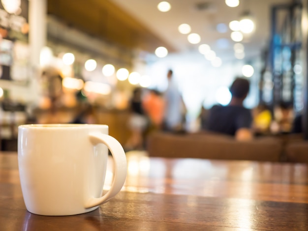 Heißer kaffeecappuccino in der weißen schale auf holztisch und unscharfen hintergrundcaféspeichern.