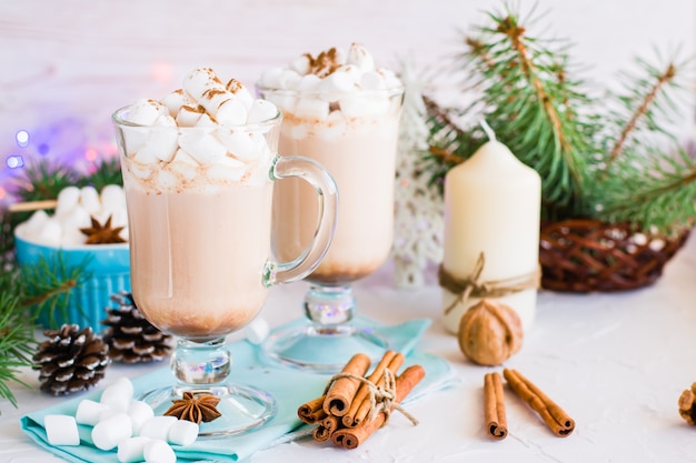 Heißer Kakao mit Eibisch und gemahlenem Zimt in den Gläsern auf dem Tisch in den Weihnachtsdekorationen